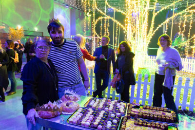 Un homme et une femme sourient à l'objectif, l'homme a la main sur l'épaule de la femme. Derrière eux, on voit la décoration lumineuse de la salle - Agrandir l'image 8 sur 22, fenêtre modale