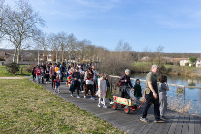 Photo du défilé, sous le soleil, le long de l'eau, on voit une centaine de familles marcher, déguisées - Agrandir l'image, fenêtre modale