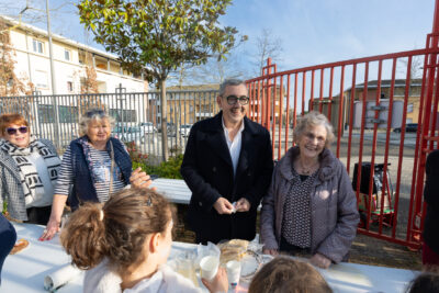 Le Maire aux côtés des bénévoles, trois femmes âgées, qui servent le goûter aux enfants avec le sourire - Agrandir l'image 17 sur 18, fenêtre modale