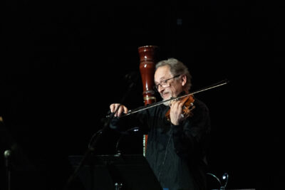 le premier violon debout émerge de l'ombre le haut de son corps éclairé doucement tandis qu'il joue avec grâce - Agrandir l'image 7 sur 8, fenêtre modale