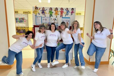 Photo de 6 femmes rassemblées en souriant qui posent devant un panneau où il y a des illustrations d'elles en super héroïnes - Agrandir l'image 6 sur 8, fenêtre modale