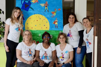 Photo de 6 femmes rassemblées avec des teeshirts sur lesquels il y a des illustrations et photomontages d'elles en super-héroïnes - Agrandir l'image 2 sur 8, fenêtre modale