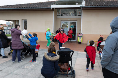 Photo de familles avec poussettes rassemblées devant la maison de quartier Pahin où est installé un stand de crêpes - Agrandir l'image 19 sur 28, fenêtre modale