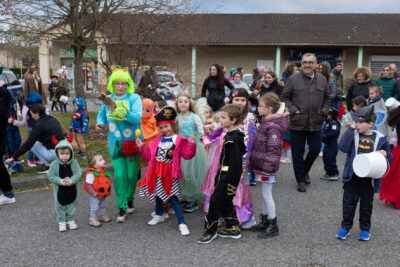 Photo d'un groupe d'enfants déguisés et de familles autour, on voit le Maire Frédéric Parre marcher parmi les familles - Agrandir l'image 20 sur 28, fenêtre modale