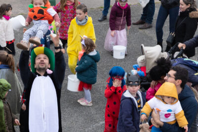 Photo portrait en plongée des familles rassemblées, on voit principalement des enfants déguisés, un père déguisé en panda porte une petite fille en hauteur - Agrandir l'image 22 sur 28, fenêtre modale