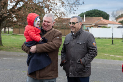 Photo du Maire qui sourit à un enfant tenu dans les bras par un homme - Agrandir l'image 8 sur 28, fenêtre modale