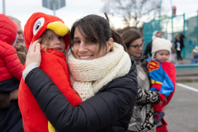 Photo d'une mère et de sa fille déguisée en oiseau, la mère porte sa fille dans les bras et les deux sourient à l'objectif - Agrandir l'image 6 sur 28, fenêtre modale
