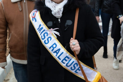 Photo d'une femme qui porte une écharpe façon Miss France sur laquelle il est écrit "Miss râleuse" - Agrandir l'image 11 sur 28, fenêtre modale
