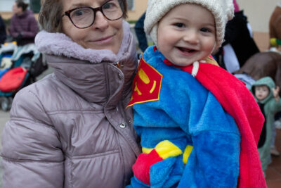 Photo d'une femme qui porte un tout petit enfant déguisé en superman, avec un bonnet blanc - Agrandir l'image 14 sur 28, fenêtre modale