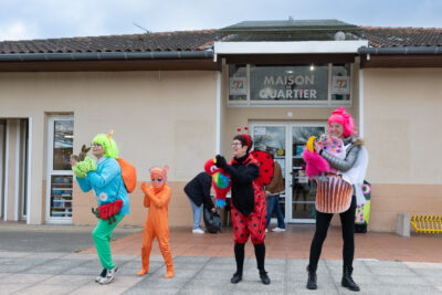 Photo de femmes et d'un enfant déguisés devant la maison de quartier qui mettent l'ambiance en applaudissant - Agrandir l'image 17 sur 28, fenêtre modale