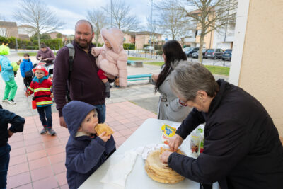 Photo d'une femme qui prépare une crêpe à donner à un petit garçon qui en mange déjà une - Agrandir l'image 18 sur 28, fenêtre modale