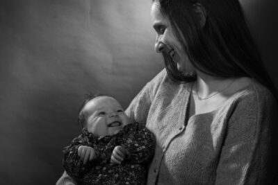 Photo portrait en noir et blanc d'une femme qui tient un bébé dans ses bras, les deux se regardent en souriant - Agrandir l'image 13 sur 21, fenêtre modale