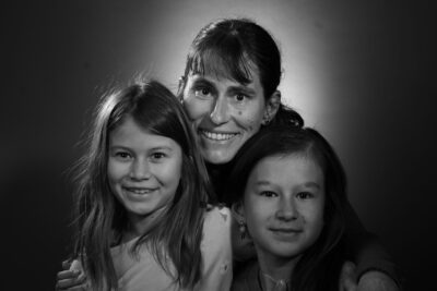 Photo d'une femme et deux jeunes filles assises qui se tiennent par les bras, et sourient à l'objectif - Agrandir l'image 10 sur 21, fenêtre modale