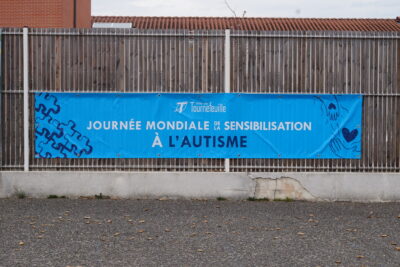 Banderole bleue accrochée à une palissade, sur laquelle il est écrit "journée mondiale de sensibilisation à l'autisme" - Agrandir l'image 11 sur 14, fenêtre modale