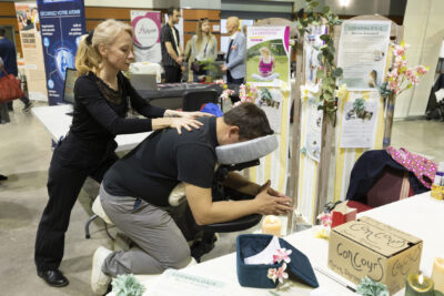 Un homme se fait masser par une femme au niveau d'un stand de sophrologie - Agrandir l'image 15 sur 20, fenêtre modale