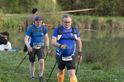 Deux hommes font de la marche nordique, dans l'herbe à proximité du lac des Pêcheurs, on voit derrière eux un pêcheur - Agrandir l'image 25 sur 32, fenêtre modale