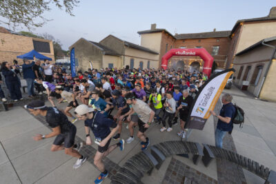 Les coureurs s'élancent au départ sur le parvis de la Mairie, le ciel est encore relativement clair, on voit le Maire tenir le pistolet qui marque le départ, debout sur un banc sur le côté - Agrandir l'image 20 sur 32, fenêtre modale