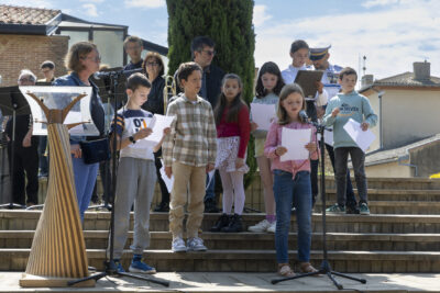 Photo d'une dizaine d'enfants qui parlent, en tenant le texte dans leur main, sur des marches - Agrandir l'image 14 sur 17, fenêtre modale