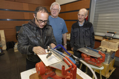 Trois hommes derrière un stand avec des machines de petite taille, un homme fait une démonstration - Agrandir l'image 13 sur 17, fenêtre modale