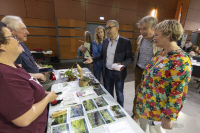 Le Maire Frédéric Parre, les élus Aurore Dufaud, Laurence Staskiewicz et Patrick Chartier échangent avec un homme et une femme qui tiennent un stand sur lequel on voit une série de photos - Agrandir l'image 1 sur 17, fenêtre modale