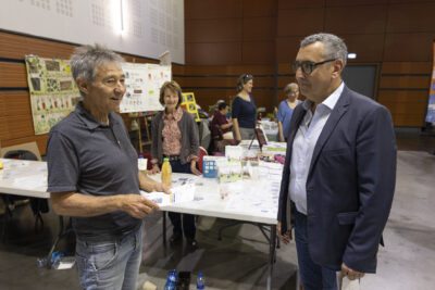 Le Maire Frédéric Parre échange avec un homme, derrière eux, des stands avec des personnes derrière - Agrandir l'image 3 sur 17, fenêtre modale