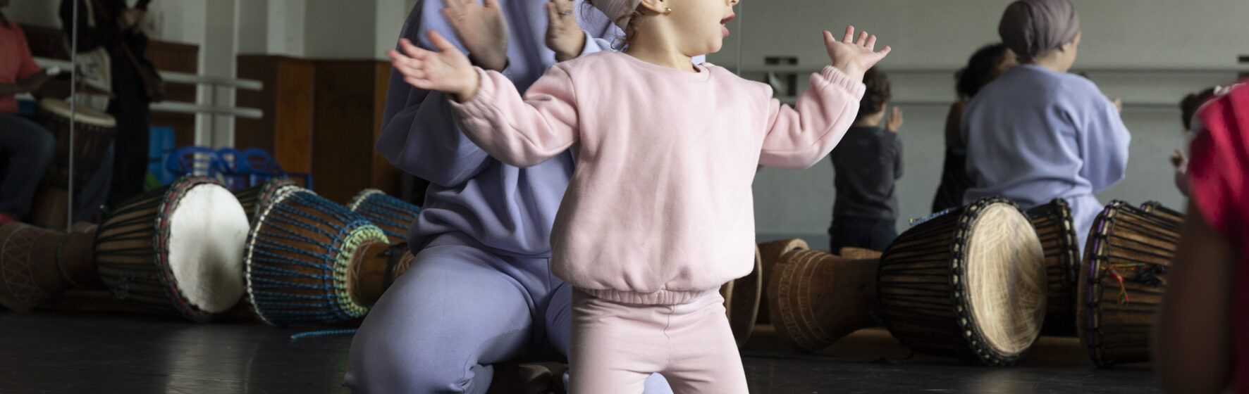 Photo d'une petite fille sur les genoux prête à applaudir dans une salle de cours de danse