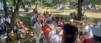 Photo de groupes de personnes de tout âge réunis autour de tables de pique-nique