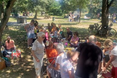 Photo de groupes de personnes de tout âge réunis autour de tables de pique-nique