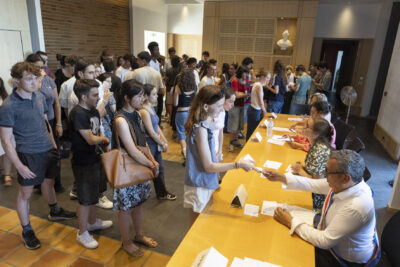 Des jeunes gens font la queue dans la salle du Conseil pour recevoir leur carte électorale des mains du Maire Frédéric Parre, des agents sont assis avec le Maire pour donner les cartes - Agrandir l'image 7 sur 10, fenêtre modale