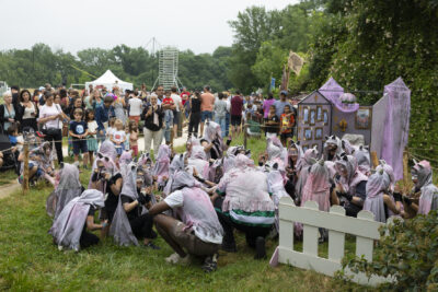 Photo d'un groupe d'enfants habillés en gris rose clair avec des animateurs, rassemblés au sol devant leur stand de la même couleur - Agrandir l'image 18 sur 24, fenêtre modale