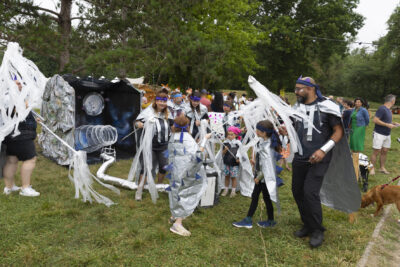 Photo d'un groupe d'enfants et animateurs habillés avec des capes argentées et des bandeaux bleus qui sont rassemblés devant leur stand - Agrandir l'image 16 sur 24, fenêtre modale