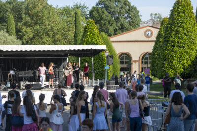 Photo paysage prise depuis le public du concert sur la scène jeunesse derrière la Mairie, des groupes de jeunes sont rassemblés pour écouter - Agrandir l'image 14 sur 16, fenêtre modale