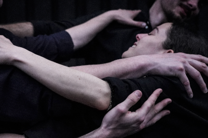 plan rapproché sur les interprètes de la pièce chorégraphique "La liesse" de la compagnie Parc, où dans une lumière froide, on voit les bras nus et les têtes des interprètes hpommes et femmes tournés les uns vers les autres, entrain de se tenir les uns les autres en se balançant comme en un seul corps collectif. - Agrandir l'image, fenêtre modale