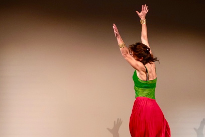 Une danseuse portant un débardeur vert et longue jupe rouge tourbillonnant sur elle même les bras levés. - Agrandir l'image, fenêtre modale
