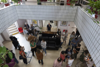 Dans le Hall lumineux de l'Ecole d'Enseignements Artistiques de Tournefeuille, vue depuis la galerie du premier étage, tapissée de carrelage blanc et agrémentée de plantes vertes luxuriantes, le public se rassemble autour des artistes, des professeurs et de la directrice de l'Ecole accompagnée de l'adjointe au maire Déléguée à la Culture qui introduisent ce temps de vernissage par un discours d'accueil. - Agrandir l'image 1 sur 7, fenêtre modale