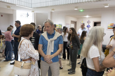 Dans le hall de l'Ecole, les discussions vont bon train entre les personnes debout rassemblées lors du vernissage de l'exposition en arts visuels. - Agrandir l'image 5 sur 7, fenêtre modale