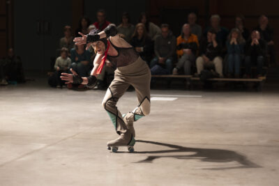 Mouvement d'entrechat effectué en rollers mains figées en un mouvement de mime face à une vitre invisible. public en arrière-plan sur des gradins modulables. - Agrandir l'image 5 sur 14, fenêtre modale