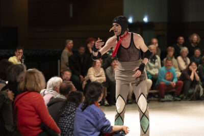 Plan rapproché sur le buste du danseur déguisé qui s'adresse au public en accompagnant son mouvement des mains - Agrandir l'image 7 sur 14, fenêtre modale