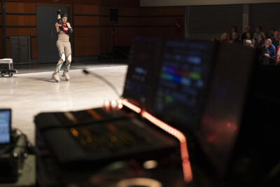 Au premier plan la console du régisseur du spectacle; en arrière-plan le danseur à rollers se tient debout main gauche soulevant son coude droit - Agrandir l'image 2 sur 14, fenêtre modale