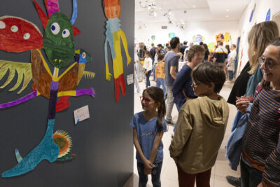 Enfants et aprents découvrent avec ravissement le fruit du travail d'exposition collective en salle d'exposition; de jolis monstres géants apparaissent au premier plan de l'image - Agrandir l'image 4 sur 13, fenêtre modale