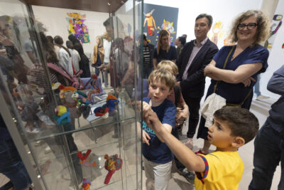 Les familles admirent de petites figurines de monstres colorés exposés dans une vitrine en salle d'exposition - Agrandir l'image 5 sur 13, fenêtre modale