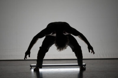 Sur cette image, le danseur qui interprète le loup, penché en avant face public, jambes et bras écartés, apparaît comme une ombre menaçante dont le corps puissant s'apprête à entrer en action - Agrandir l'image 2 sur 10, fenêtre modale