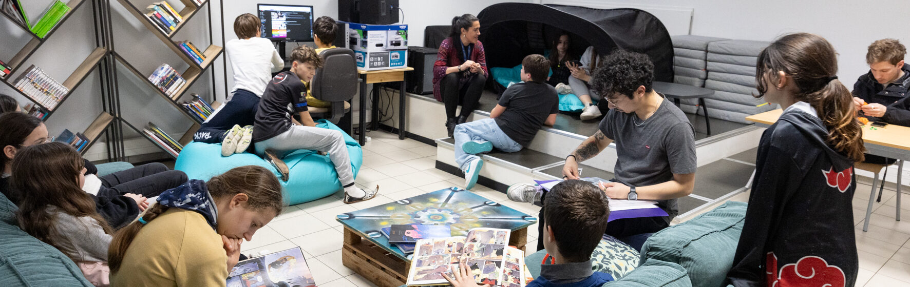 Photo d'une salle conviviale avec canapés, ordinateurs, et des jeunes répartis dans la pièce
