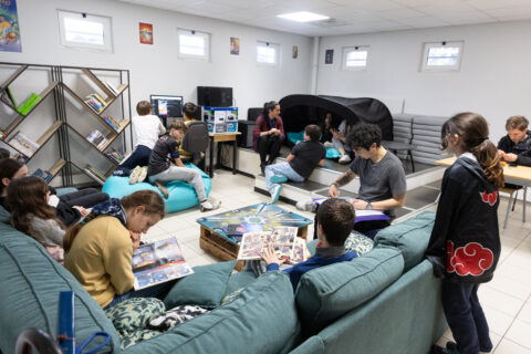 Photo d'une salle conviviale avec canapés, ordinateurs, et des jeunes répartis dans la pièce