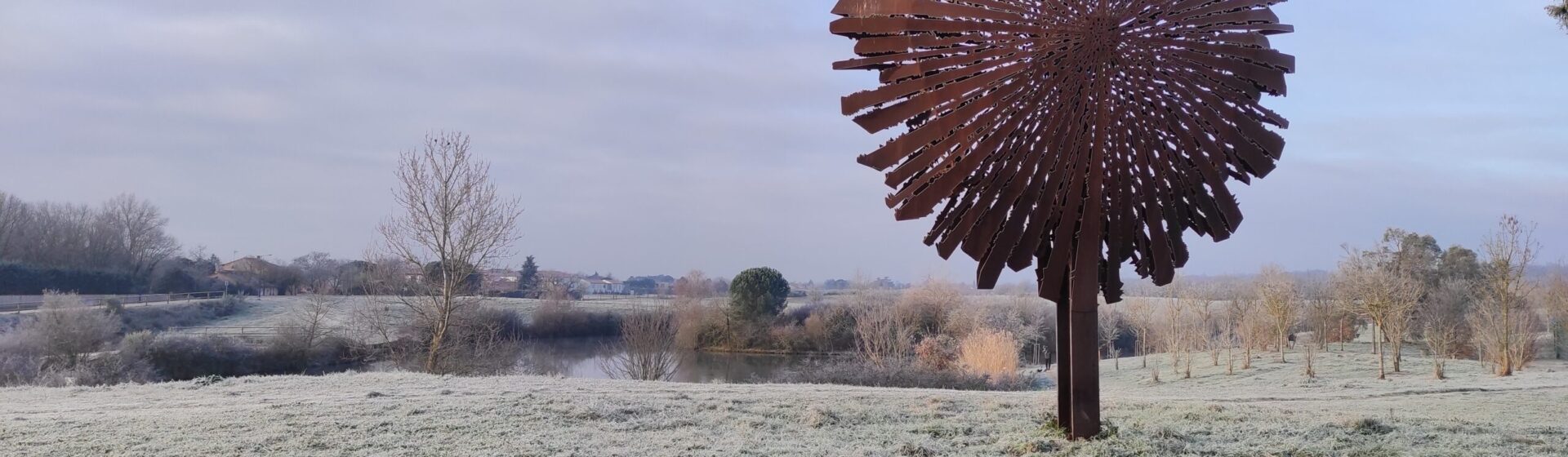 Photo du lac de l'Oustalet par temps hivernal et vue sur la sculpture en métal qui a une forme d'arbre
