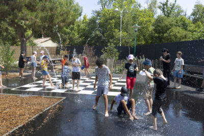 Photo d'une cour d'école avec des enfants qui jouent avec des jets d'eau - Agrandir l'image 14 sur 18, fenêtre modale