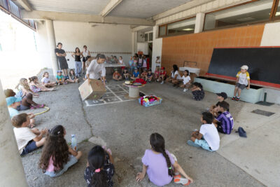 Photo d'enfants rassemblés en cercle sous un préau dans une cour - Agrandir l'image 12 sur 18, fenêtre modale