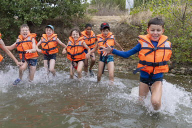 Photo d'un groupe d'enfants portant des gilets de sauvetage qui court dans l'eau