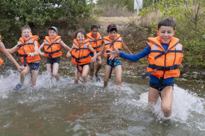 Photo d'un groupe d'enfants portant des gilets de sauvetage qui court dans l'eau - Agrandir l'image, fenêtre modale