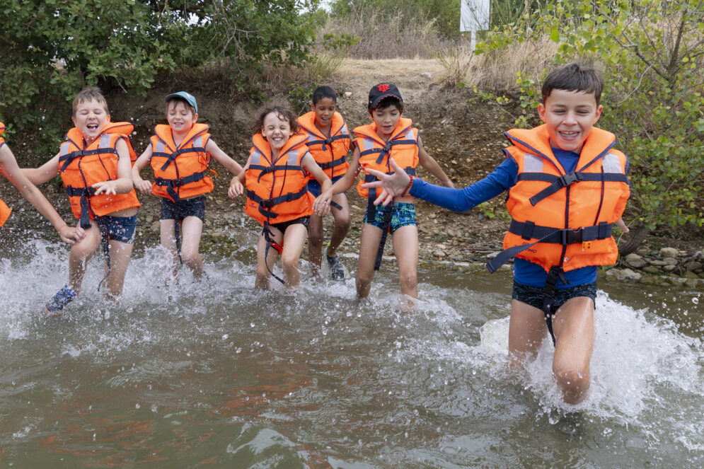 Photo d'un groupe d'enfants portant des gilets de sauvetage qui court dans l'eau
